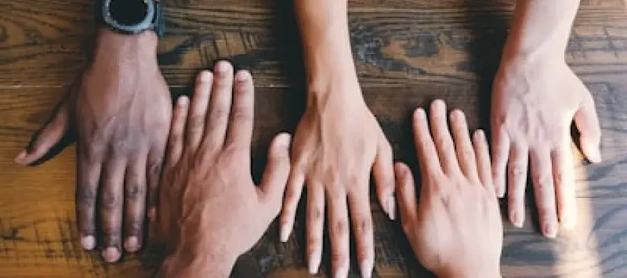 a picture showing palm down hands on the table from different minority background people
