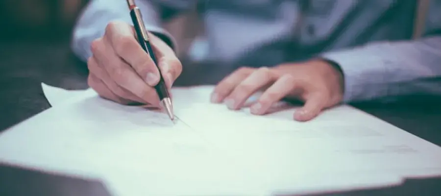 Person writing on paper with pen