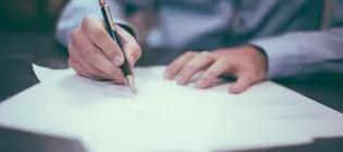 Person writing on paper with pen