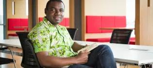 Smiling black ethnic person sitting on a chair looking at the camera