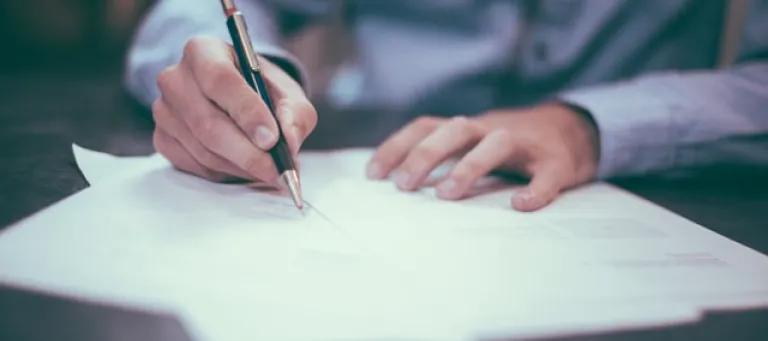 Person writing on paper with pen