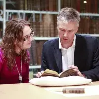 Two people listing a gaelic book