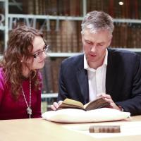 Two people listing a gaelic book