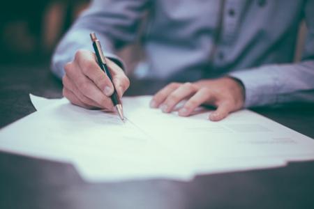 Person writing on paper with pen