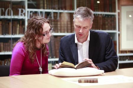 Two people listing a gaelic book