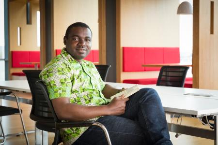 Smiling black ethnic person sitting on a chair looking at the camera