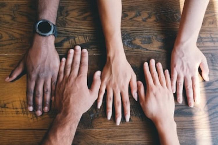 a picture showing palm down hands on the table from different minority background people