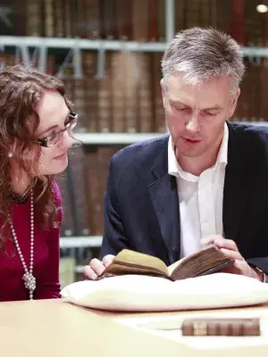 Two people listing a gaelic book