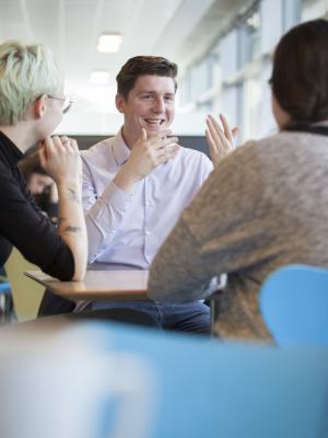 Person talking to two other people in a cafeteria 